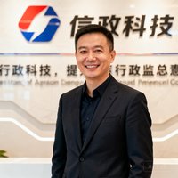某科技企业行政总监张总的商务职业照，身着深色西装面带微笑，背景为公司品牌墙。